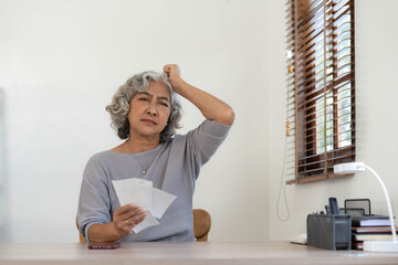 Worried Senior woman having problem about Financial economic crisis. Stressed Asian Elderly male calculate family budget, Debts, monthly expenses with calculator and laptop computer at home