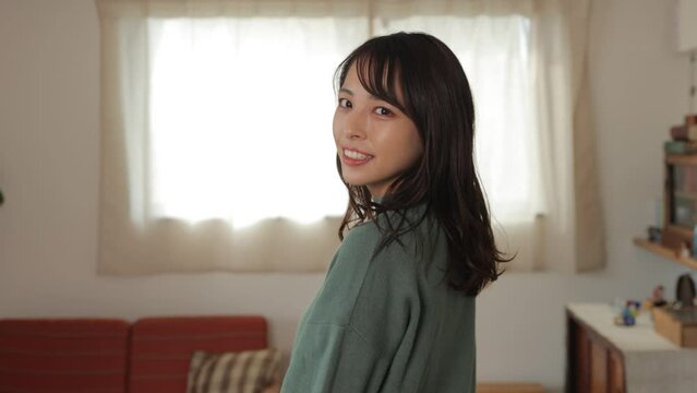 Beautiful asian girl turns around and smiles in her room. Medium shot.