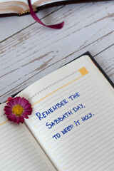 Remember Sabbath Day to keep it holy, handwritten text in a notebook with Holy Bible Book on wooden...