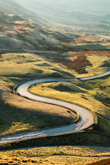 Winding road bathed in sunlight. Rolling Green hills. The road to Edale, Peak District Uk. 