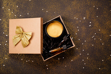 Cosmetic products for skin care in a gift box on a black background with sparkles. Gift for New...