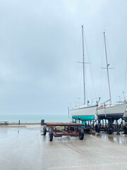 Bateaux à voile amarrés côte-à-côte sur les rampes des remorques. Voiliers sur un quai. Élévateurs à bateaux dans une marina par une journée nuageuse et grise.