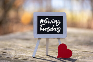 #Giving Tuesday text message on chalkboard easel with red heart on soft bokeh background copy space