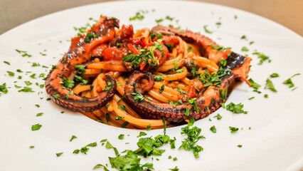 Spaghetti con sugo di pomodoro, polpo e prezzemolo serviti come primo piatto in un ristorante