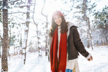 Happy woman standing among snowy trees and enjoying first snow. Holidays, rest, travel concept