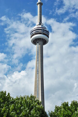View of CN Tower from a park in Toronto, Canada. CN Tower against a blue sky with clouds in...