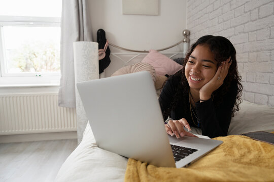Teenage girl using laptop on bed at home
