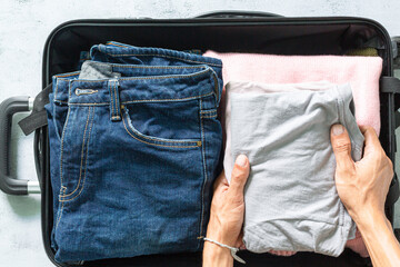 Human hand packing clothes in suitcase,Close up of businesswoman packing clothes into travel bag -...