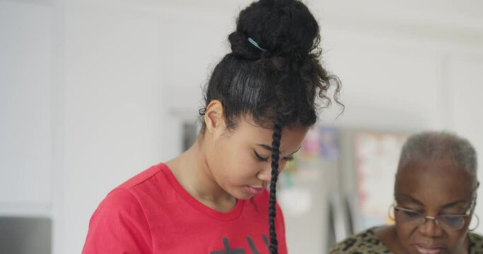 Senior woman and teenage girl preparing food in kitchen