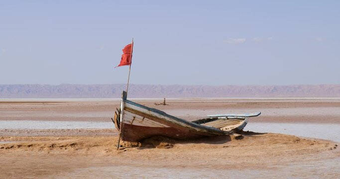 Salt lake in Tunisia Chott el Djerid during a sunny windy day. Largest salt lake in the Sahara Desert. Tourist destination. Travel the world. Boat on the dry lake. Mysterious landscape. 
