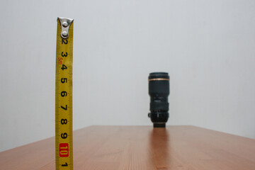 Photographers' equipment. A lens in the distance with a meter in close-up on a brown table and a...