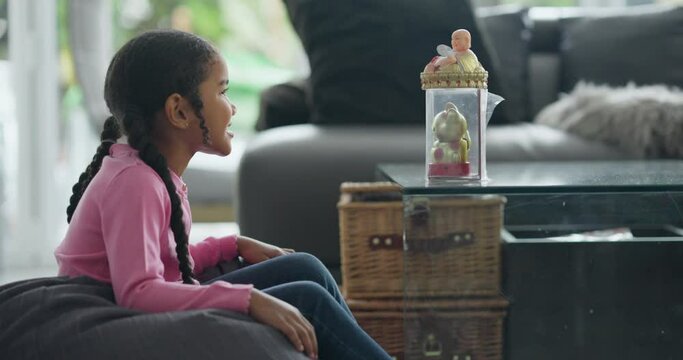 Smiling girl looking at Maneki-neko and Laughing Buddha figurines at home