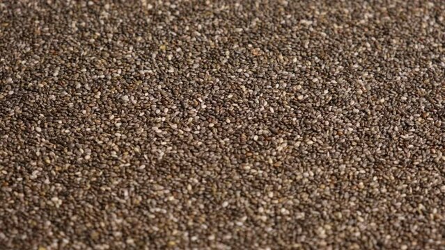 Chia Seeds Wallpaper. Raw Chia Seeds Rotating on Turntable. Close Up, Top View, Macro. Superfood. Spinning. Full Frame. Food Background. Shiny textured White, Gray and Brown Chia. Paleo Diet Concept.