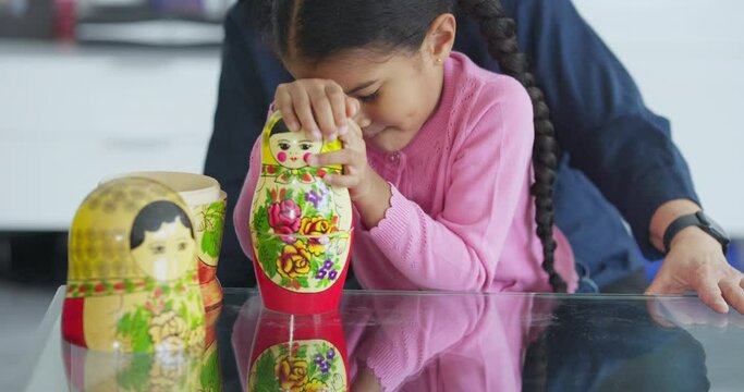 Senior woman assisting granddaughter playing with nested dolls