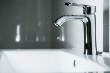 Clean water is dripping from the faucet in the bathroom. Selective focus.