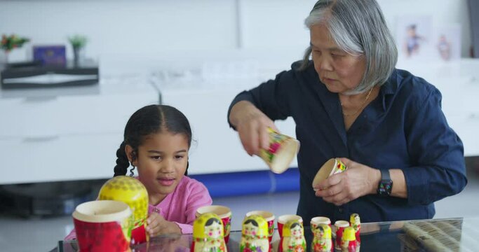 Senior woman with granddaughter playing with nested dolls