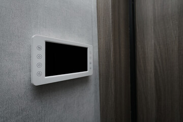 Security system device with empty black screen mounted on wall inside of apartment side close view