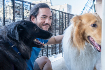 Latin guy with dogs enjoying leisure time on the balcony. Copy space.