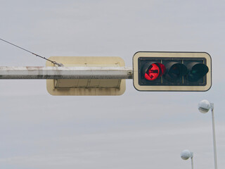Close-up photo of a red traffic light on a metal pole with a misty sky in the background