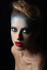 Make-up, hairstyle and fashion concept. Studio portrait of beautiful woman with fancy and futuristic blue, gray make-up and red lipstick. Model with blue eyes looking at camera with seductive look