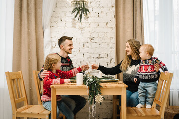 Happy family couple with two children relaxing together. Christmas tree and home decorated interior. Celebration New Year. Mother, father, daughter and son sitting at the festive table in living room.