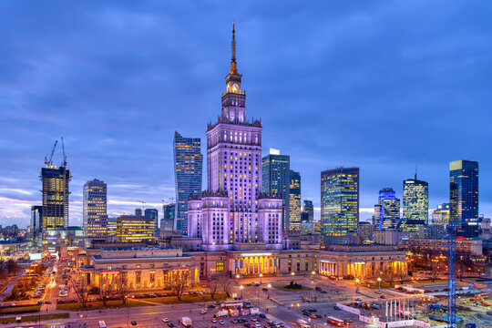 Warsaw, Poland - January 22, 2020: High angle view panorama of Warszawa cityscape skyline with centralna train station and palace of culture night evening illuminated dark urban office