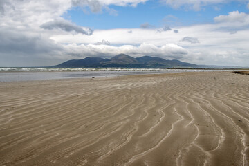 Mourne mountains from Tyrella Beach beach. Waves marked on the sand with mountains in the background. Nature reserve in Northern Ireland	