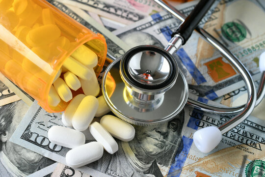 Stethoscope laying on medicine white pills & money with RX prescription drug bottle HSA FSA costs 
