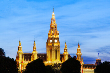 Fototapeta na wymiar Spires and clock tower of the Vienna gothic Rathaus illuminated at sunset