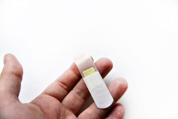 A medical patch on a man's arm on a white background. A yellow patch on the wound on his arm.