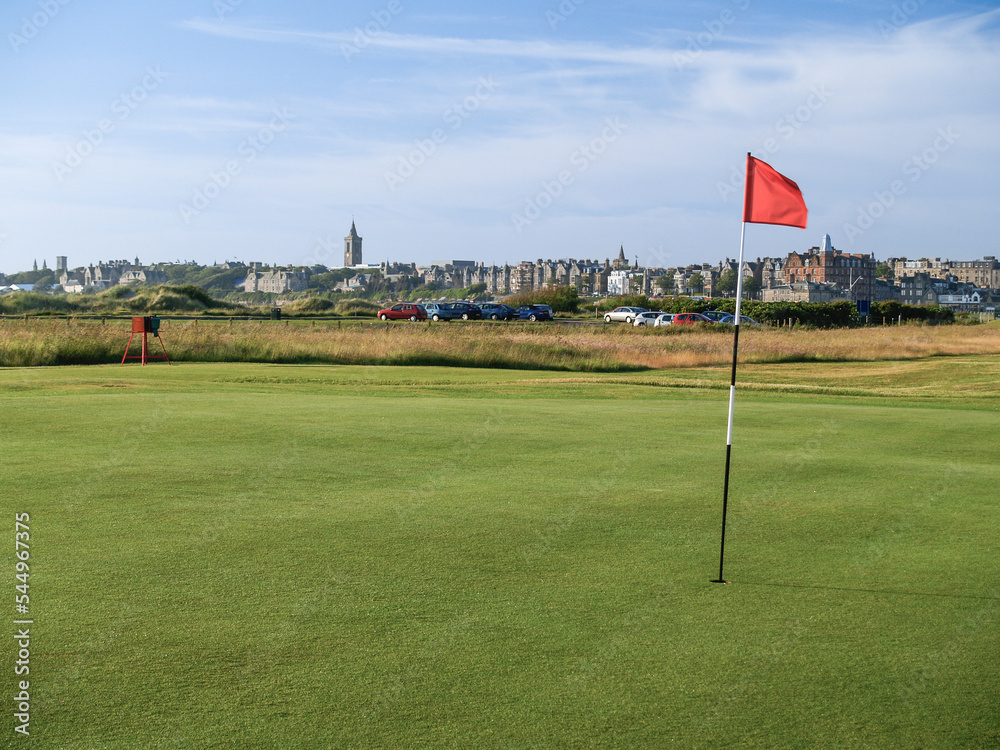 Sticker Red hole flag on golf course with urban skyline behind