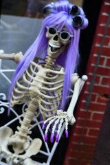 Funny skeleton in wig as outdoor Halloween decoration.