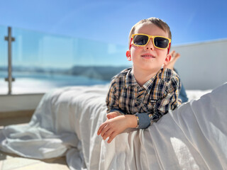 Boy wearing sunglasses and lying on bed in patio