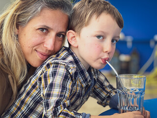 Close-up of smiling mother with son drinking water