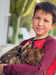Close-up of smiling boy carrying cat in yard
