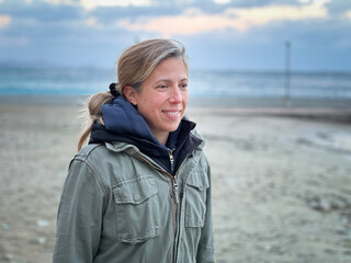Smiling woman in winter coat standing at beach