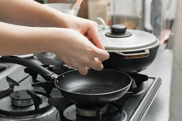 hand of a woman opening an egg to fry it in a small frying pan, preparing a typical Colombian...