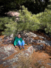 Boy sitting on rock under tree shadow in forest