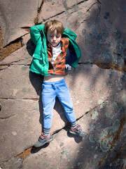 Thoughtful boy lying on rock formation