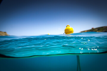 Yellow buoy floating on sea against clear sky