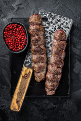 Urfa kebab, ground beef and lamb meat grilled on skewers. Black background. Top view