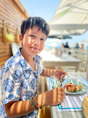 Smiling boy eating pizza at outdoor restaurant