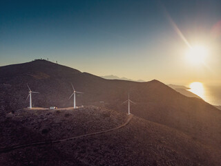 Wind turbines on mountain against sunset sky