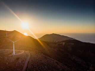 Wind turbines on mountain against sunset sky