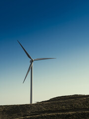 Wind turbine on mountain against blue sky
