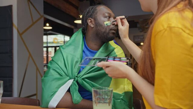 Woman applying face paint on soccer fans face