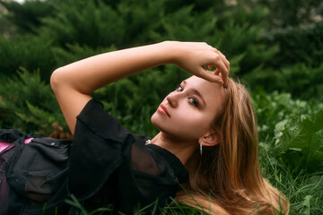 Fresh natural portrait of a cute blonde girl lying on the grass. Fashion snapshot of a beautiful young woman with clean skin, long blond hair and dark green eyes.