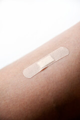 A patch on a man's white leg. The patch on the leg wound is a close-up.