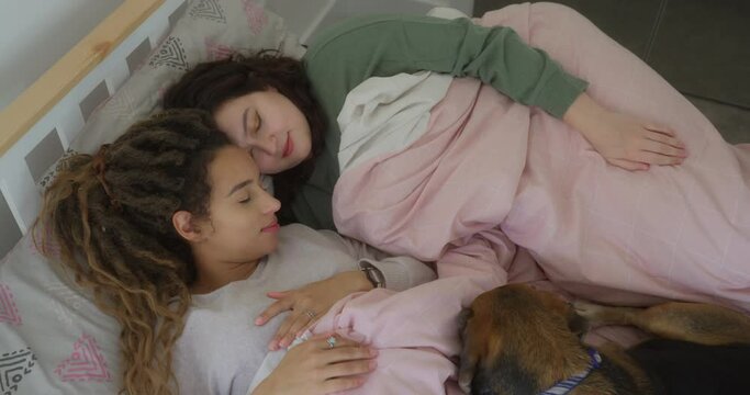 Lesbian couple with dog in bed