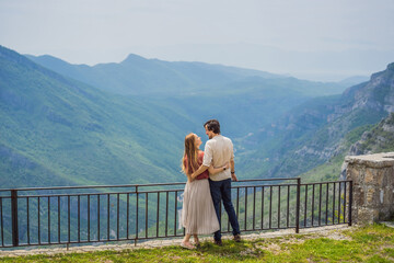 Fototapeta na wymiar Happy couple tourists on background of Blue river running through green valley toward distant mountains. Beautiful mountains of Montenegro and the river Cievna